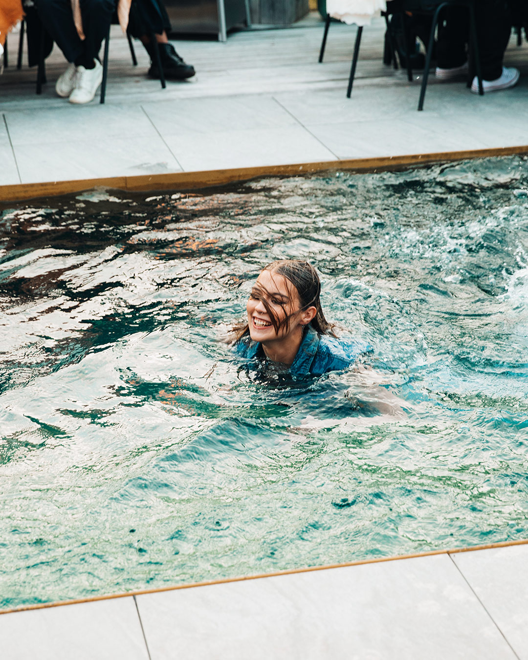 Woman laughing in a pool fully clothed