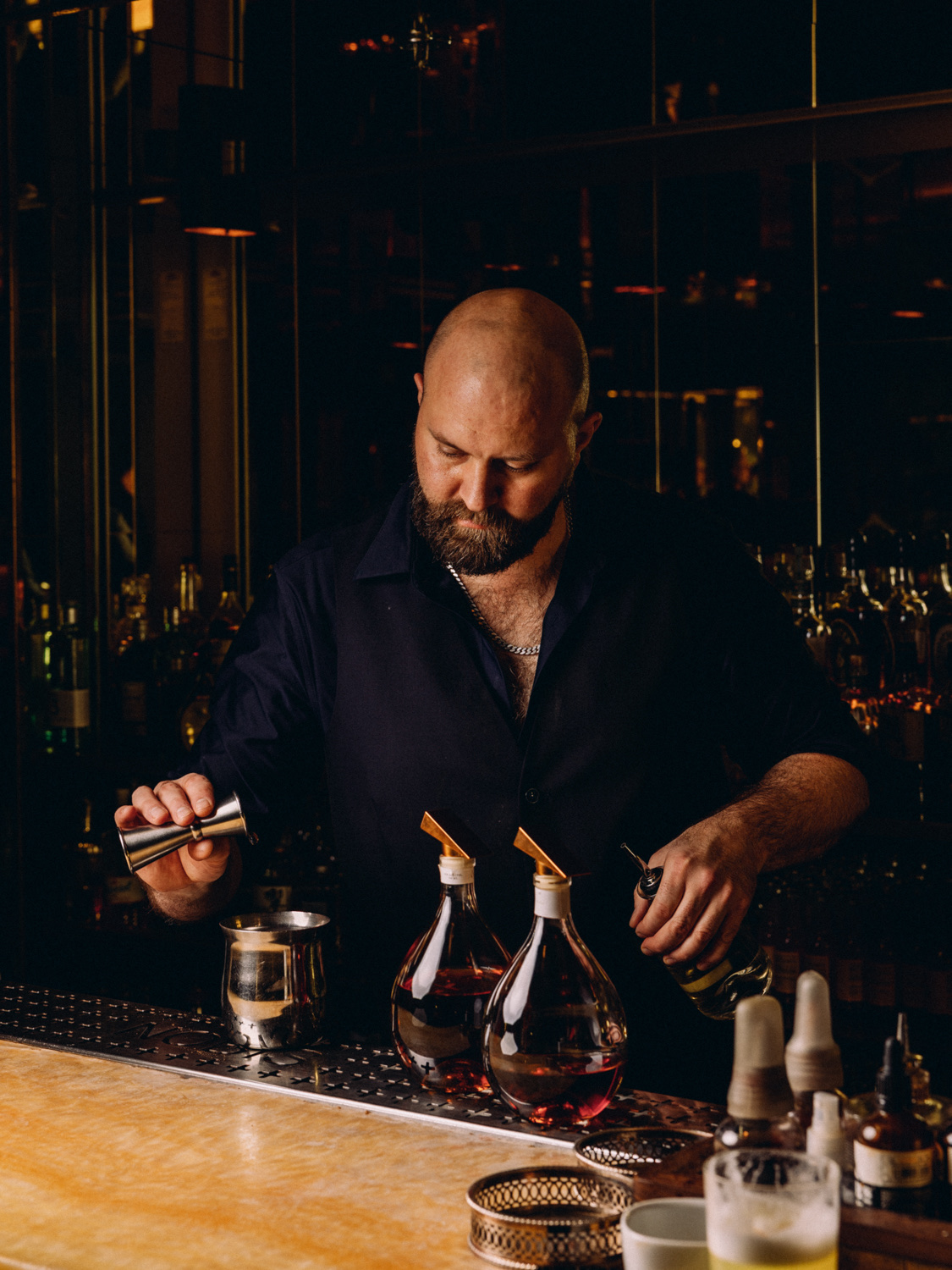 Bartender measuring spirits with ÓGIN bottles