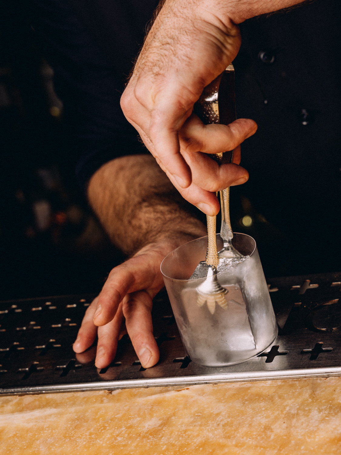 Hands stirring ice in a mixing glass