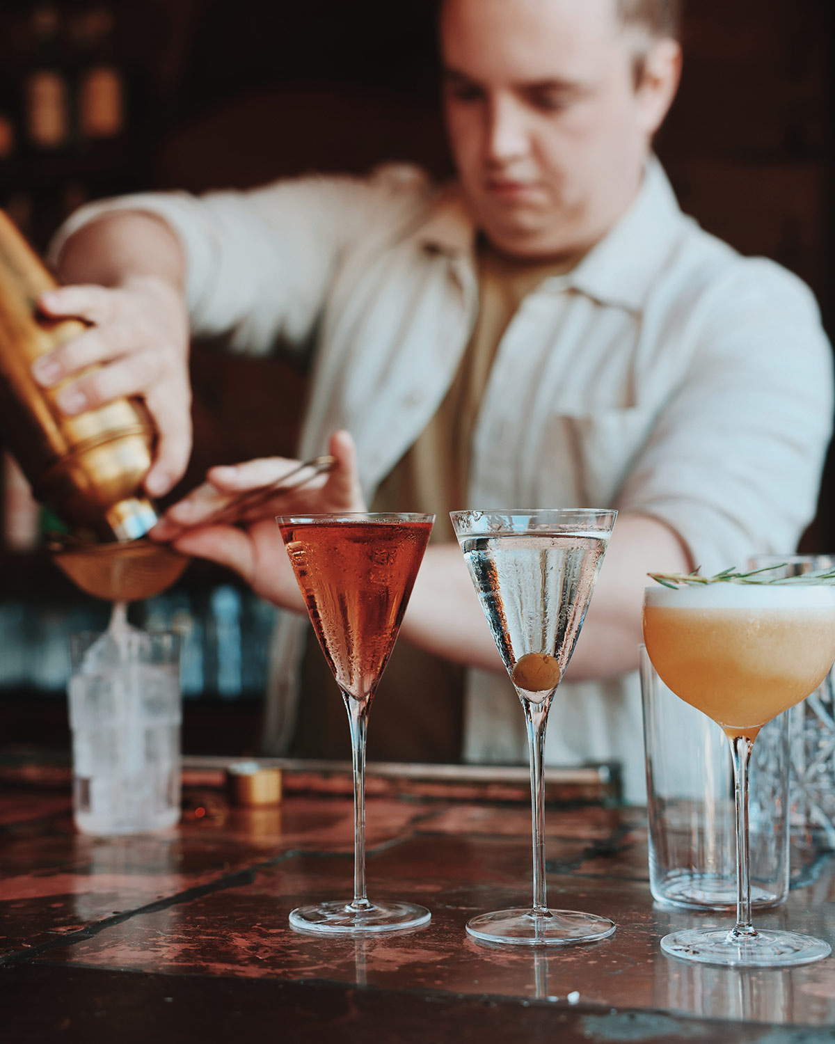 Bartender pouring cocktails from a gold shaker