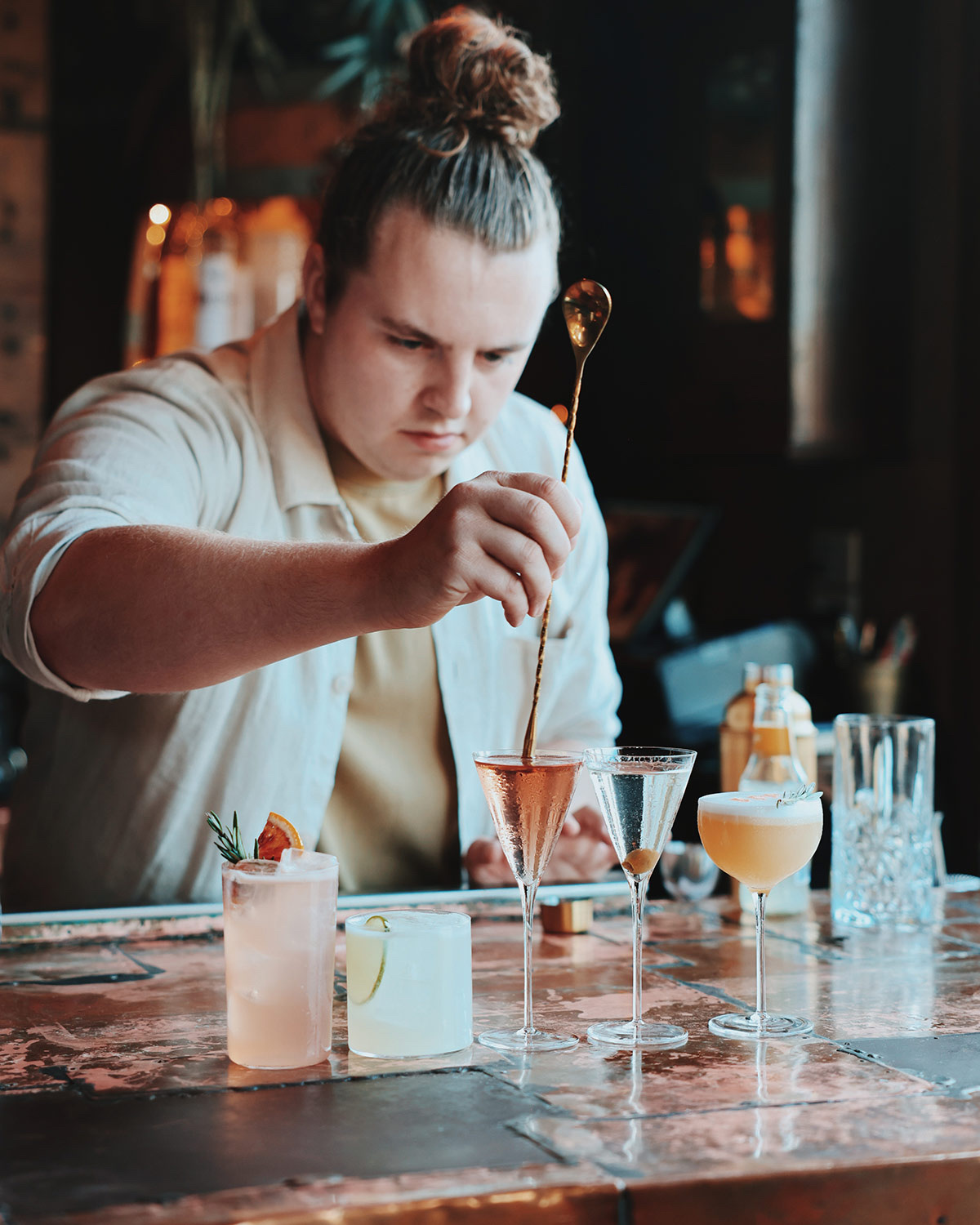 Bartender stirring a lineup of cocktails