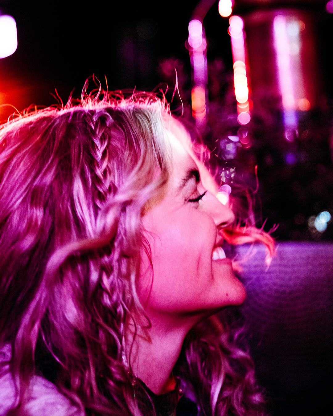 Woman laughing in pink neon nightlife glow